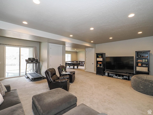 living room featuring light carpet, a textured ceiling, and a healthy amount of sunlight