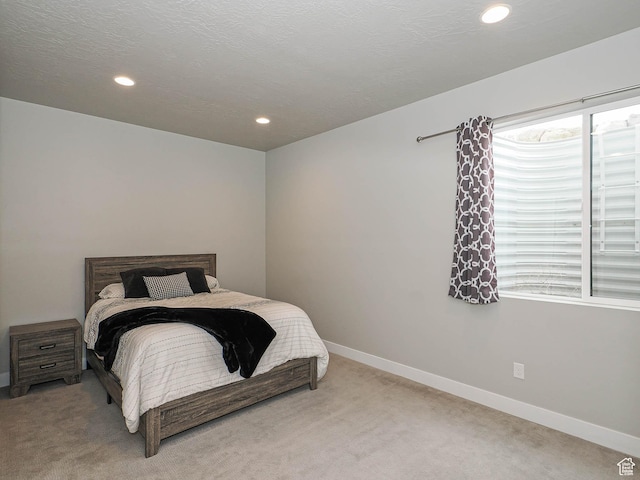 bedroom featuring recessed lighting, light colored carpet, a textured ceiling, and baseboards