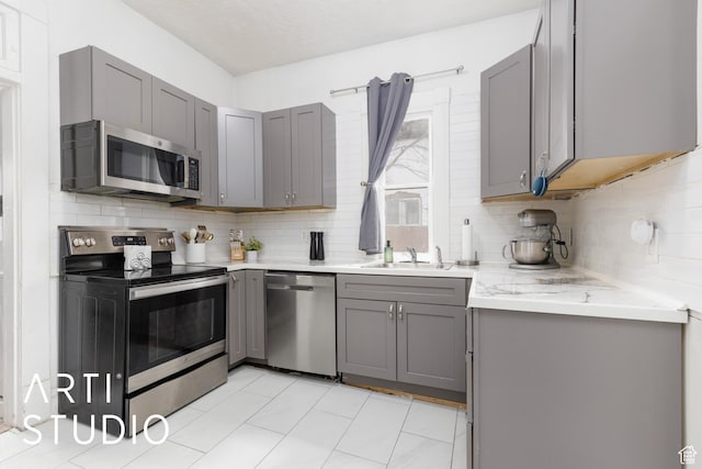 2516 S Orchard Ave, Ogden, UT 84401 - kitchen with a sink, tasteful backsplash, gray cabinets, and stainless steel appliances