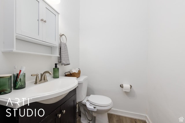 2516 S Orchard Ave, Ogden, UT 84401 - half bathroom featuring toilet, vanity, baseboards, and wood finished floors