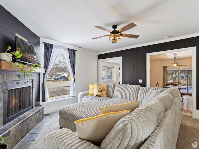 3911 W 2250 N, Corinne, UT 84307 - carpeted living room featuring a textured ceiling, ceiling fan, a tiled fireplace, and wood walls