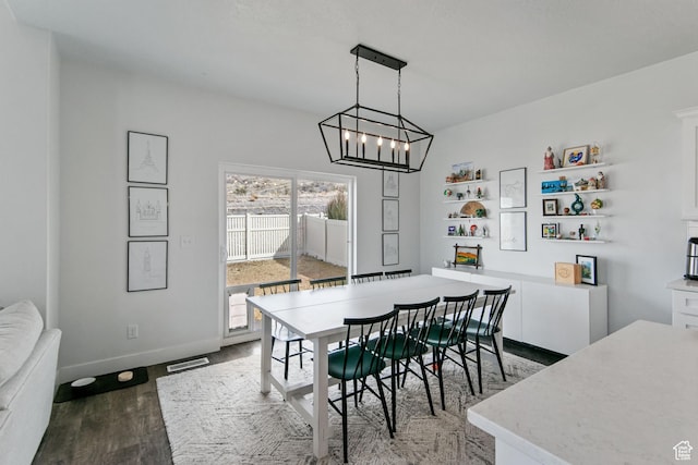 dining space featuring baseboards, wood finished floors, visible vents, and a chandelier
