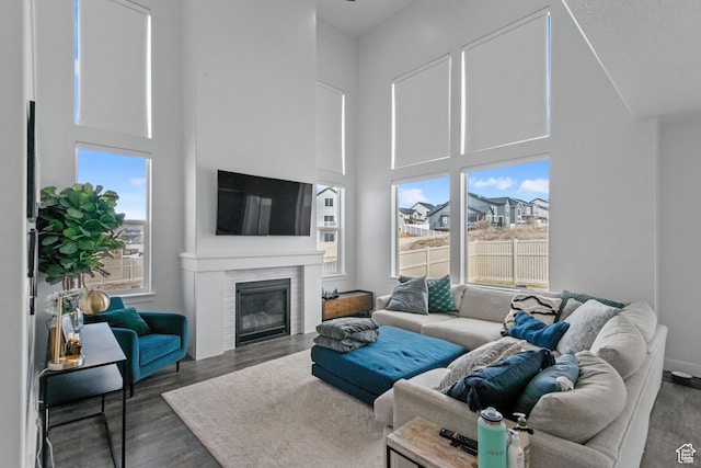 living area featuring a high ceiling, wood finished floors, and a tile fireplace