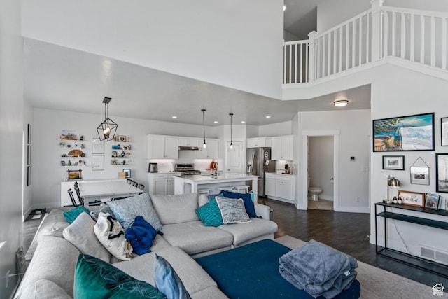 living room featuring visible vents, baseboards, recessed lighting, dark wood-style flooring, and a towering ceiling