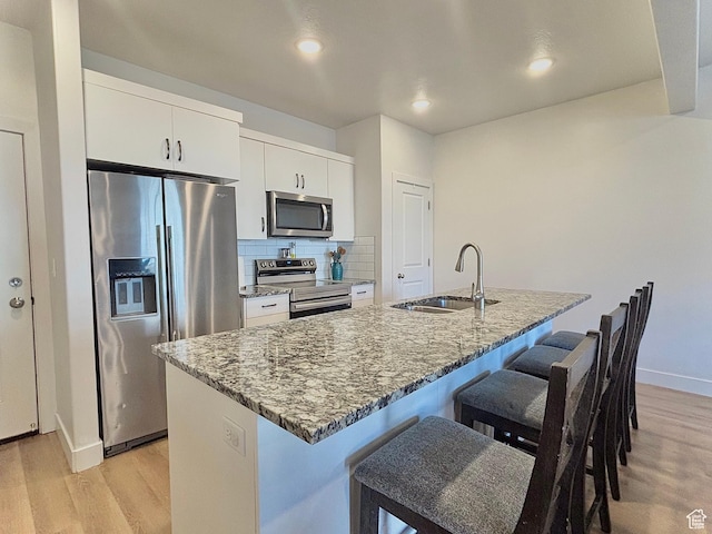 kitchen with light wood-style floors, a breakfast bar, a sink, and stainless steel appliances