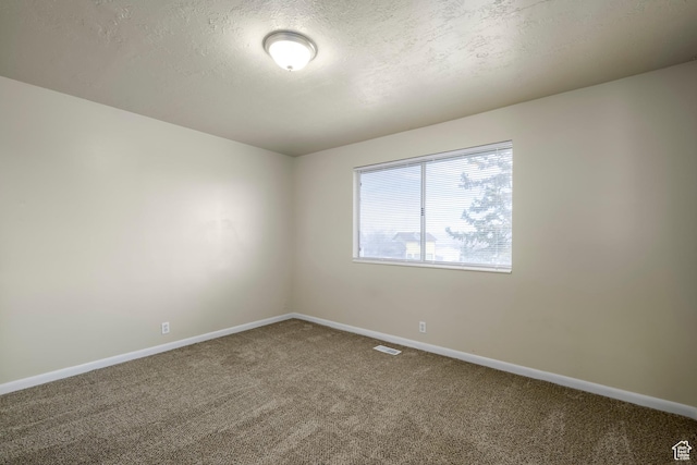 carpeted empty room with visible vents, baseboards, and a textured ceiling