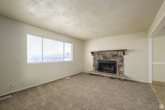 unfurnished living room with a textured ceiling, baseboards, visible vents, a fireplace, and light carpet