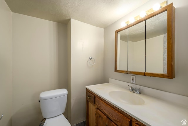 bathroom with vanity, toilet, and a textured ceiling