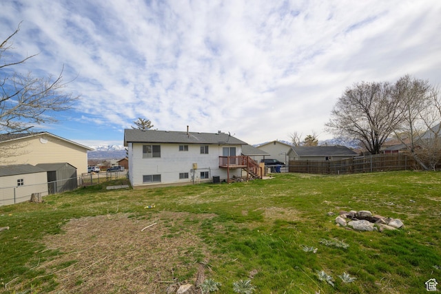 rear view of house with stairway, a fenced backyard, a lawn, and a wooden deck