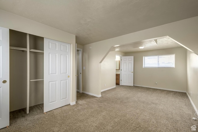 unfurnished bedroom featuring a closet, arched walkways, baseboards, and carpet floors