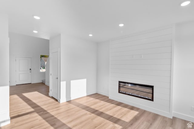 unfurnished living room with recessed lighting, a large fireplace, and light wood-style floors