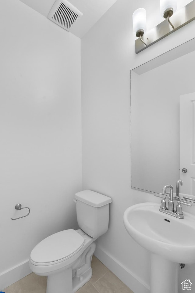 half bath with tile patterned flooring, visible vents, baseboards, toilet, and a sink