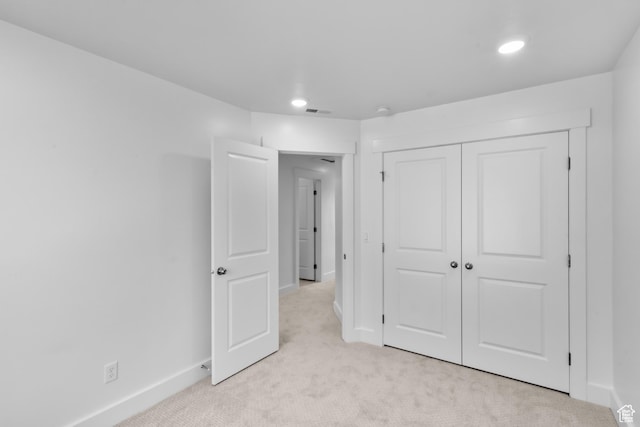 unfurnished bedroom featuring visible vents, baseboards, a closet, and light carpet