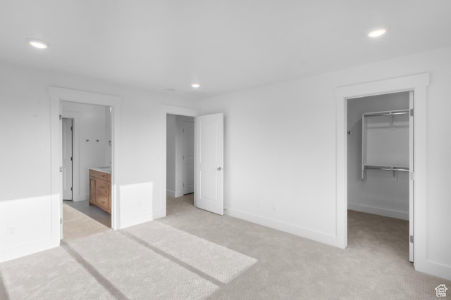 unfurnished bedroom with recessed lighting, light carpet, and a spacious closet