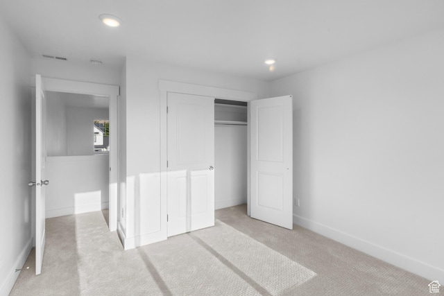 unfurnished bedroom with baseboards, visible vents, recessed lighting, a closet, and light colored carpet