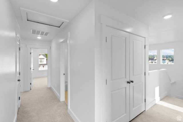 corridor with visible vents, baseboards, attic access, light carpet, and recessed lighting