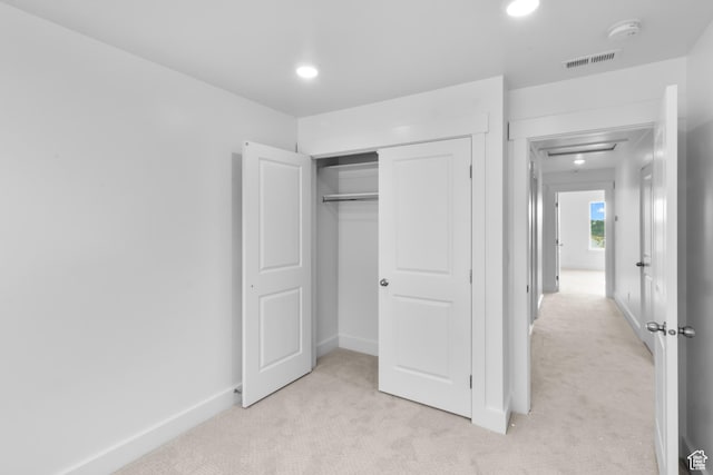 unfurnished bedroom featuring light carpet, visible vents, a closet, and baseboards