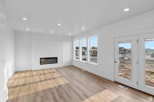 unfurnished living room with visible vents, a large fireplace, baseboards, recessed lighting, and light wood-style flooring