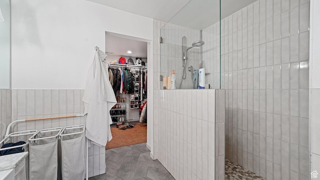 bathroom with a spacious closet, tile patterned flooring, and a walk in shower