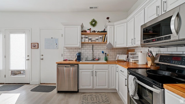 kitchen featuring visible vents, a healthy amount of sunlight, appliances with stainless steel finishes, and wood counters