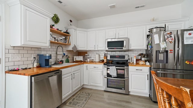 kitchen featuring butcher block countertops, appliances with stainless steel finishes, visible vents, and a sink