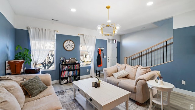 living room with stairway, a notable chandelier, visible vents, and light wood finished floors