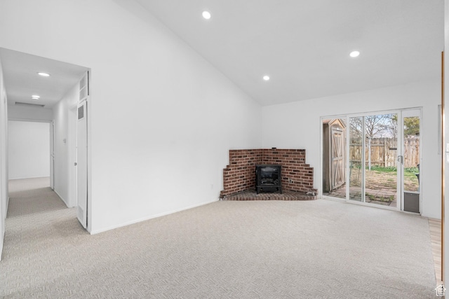 unfurnished living room with high vaulted ceiling, carpet, recessed lighting, and a wood stove