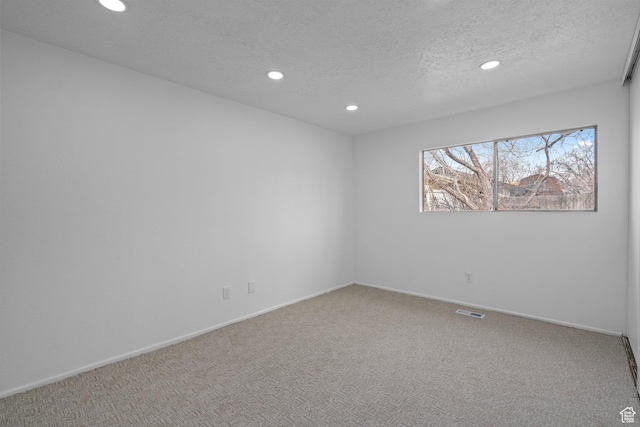 carpeted spare room with visible vents, recessed lighting, a textured ceiling, and baseboards