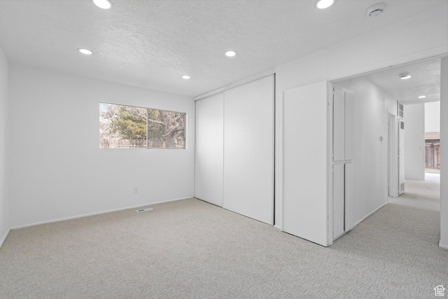 interior space featuring recessed lighting, visible vents, light carpet, and a textured ceiling