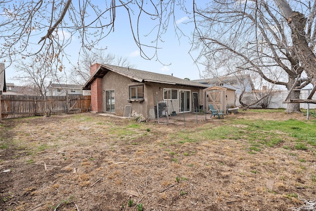 back of property with a storage shed, an outdoor structure, a fenced backyard, and stucco siding