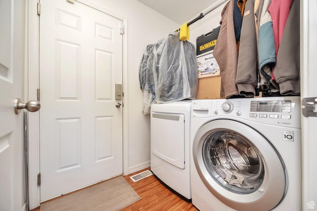laundry room with visible vents, light wood finished floors, laundry area, and washing machine and clothes dryer
