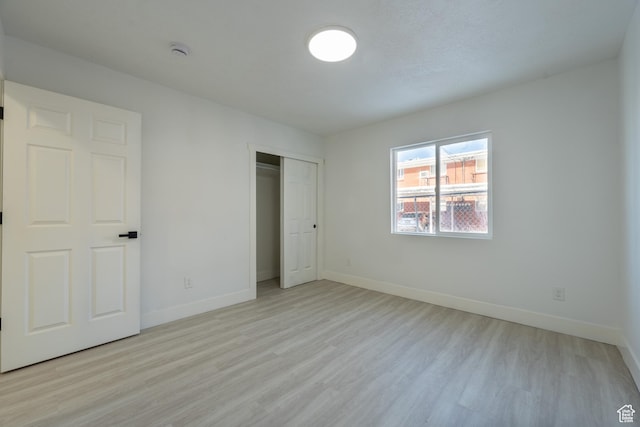 unfurnished bedroom featuring a closet, baseboards, and light wood finished floors