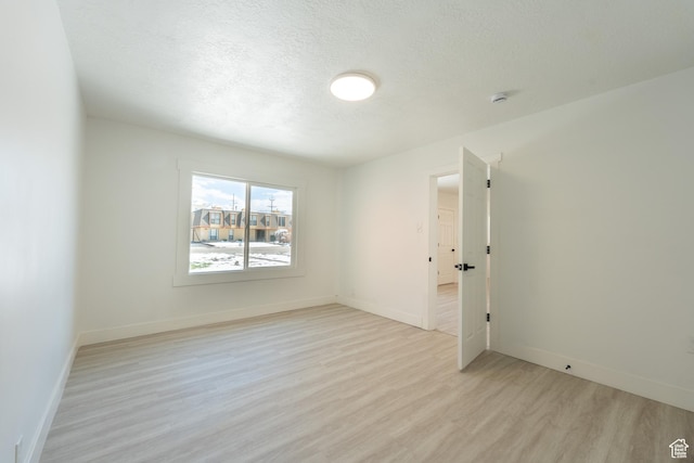 unfurnished room featuring baseboards, a textured ceiling, and light wood finished floors