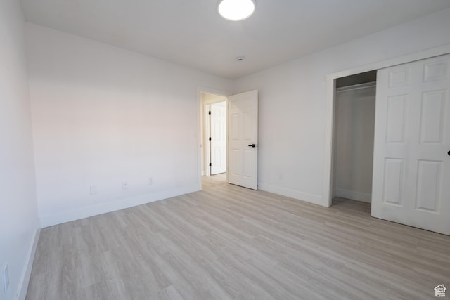 unfurnished bedroom featuring light wood finished floors, a closet, and baseboards