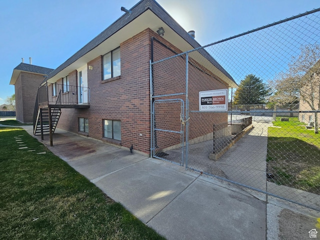 3673 S 2200 W Unit 15, West Valley City, UT 84119 - view of property exterior featuring stairway, a yard, fence, and brick siding
