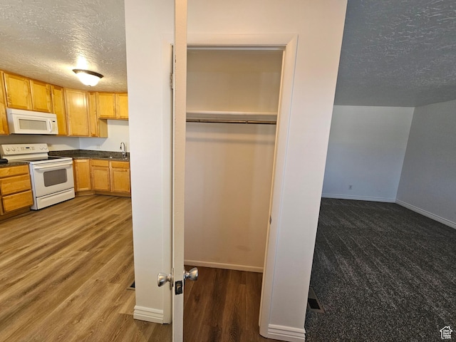 3673 S 2200 W Unit 15, West Valley City, UT 84119 - kitchen with dark countertops, baseboards, white appliances, a textured ceiling, and a sink