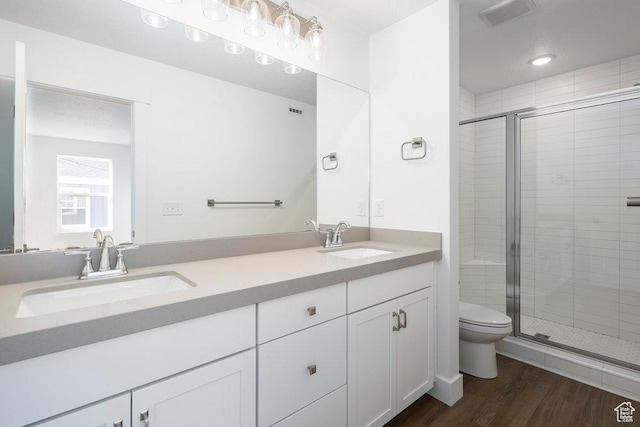 bathroom featuring toilet, wood finished floors, a stall shower, and a sink
