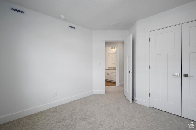 unfurnished bedroom with light colored carpet, visible vents, a closet, and baseboards