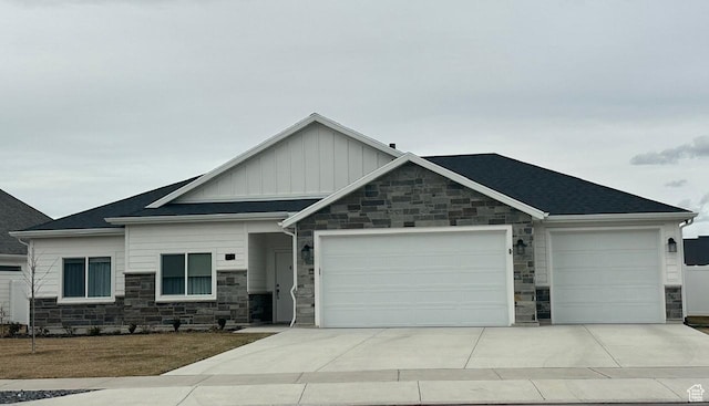 view of front of property with driveway, stone siding, roof with shingles, board and batten siding, and a garage
