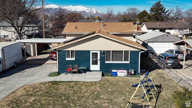 view of front of home featuring brick siding, fence, concrete driveway, a front yard, and a mountain view