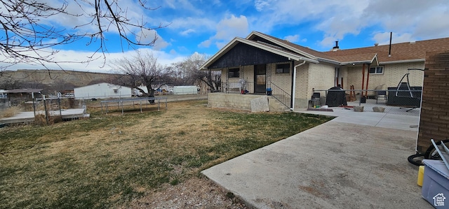 1433 W 2060 N, Helper, UT 84526 - back of property featuring a trampoline, covered porch, brick siding, and a patio