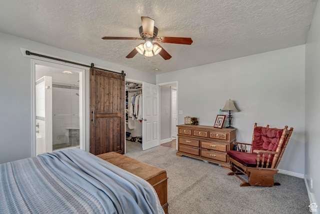 bedroom with a spacious closet, connected bathroom, light colored carpet, a barn door, and a closet