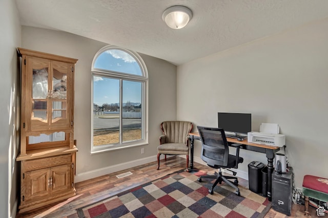 office area with visible vents, baseboards, a textured ceiling, and wood finished floors