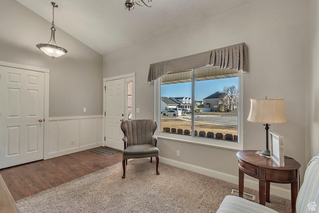 living area with a wainscoted wall, wood finished floors, baseboards, and vaulted ceiling
