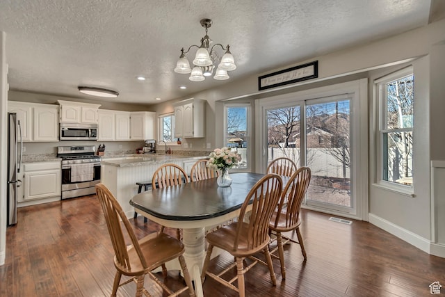 dining space featuring baseboards, dark wood-type flooring, an inviting chandelier, and a textured ceiling