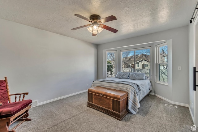 carpeted bedroom with a ceiling fan, baseboards, visible vents, and a textured ceiling