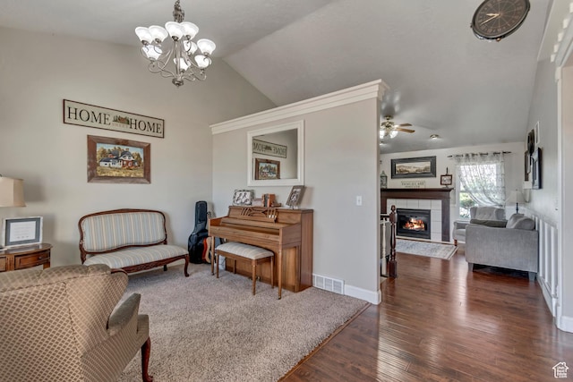 sitting room featuring visible vents, vaulted ceiling, ceiling fan with notable chandelier, a fireplace, and dark wood-style floors