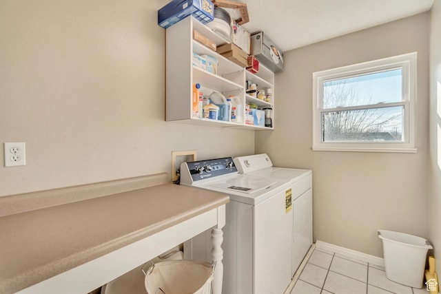clothes washing area featuring baseboards, light tile patterned flooring, washing machine and dryer, and laundry area