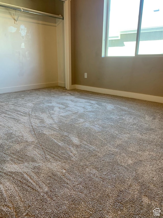 unfurnished bedroom featuring baseboards, carpet flooring, and a closet