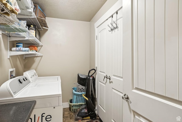 laundry area with laundry area, washing machine and dryer, stone finish flooring, baseboards, and a textured ceiling